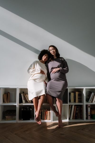 Photo by cottonbro studio: https://www.pexels.com/photo/2-pregnant-women-in-midi-dresses-sitting-on-bookshelf-5853660/